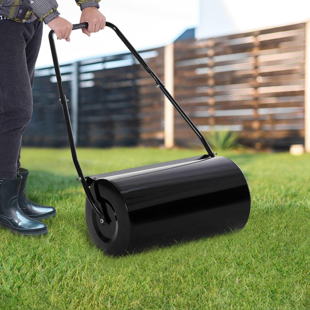 Manual lawn roller pushed across grass with black drum and handle