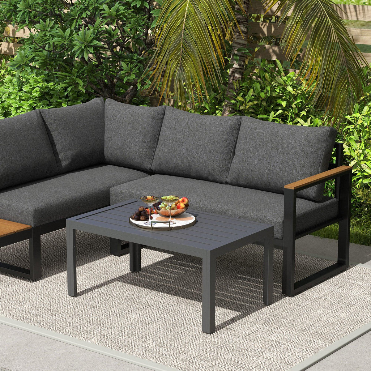 Rectangular slat-top outdoor side table with dark grey steel frame beside outdoor sofa