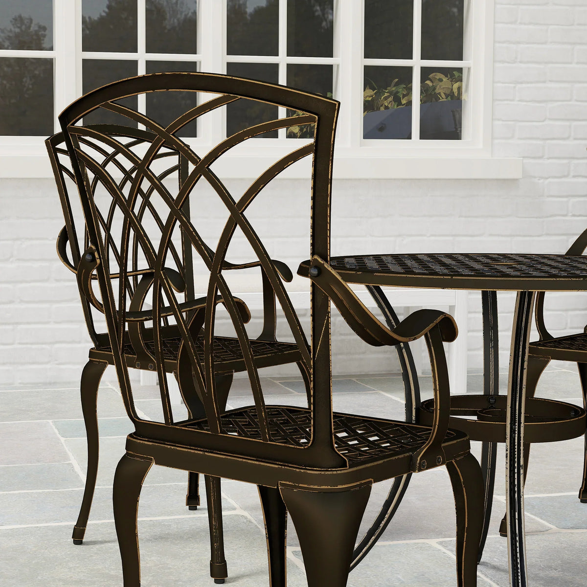 Bronze lattice armchair beside round table with slatted tabletop and curved arms