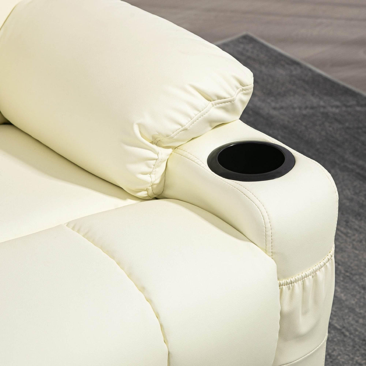 Cream armrest cup holder on faux leather recliner with visible stitching