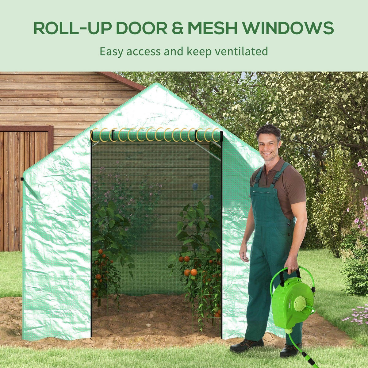 Green walk-in polytunnel greenhouse with roll-up door and mesh windows at garden