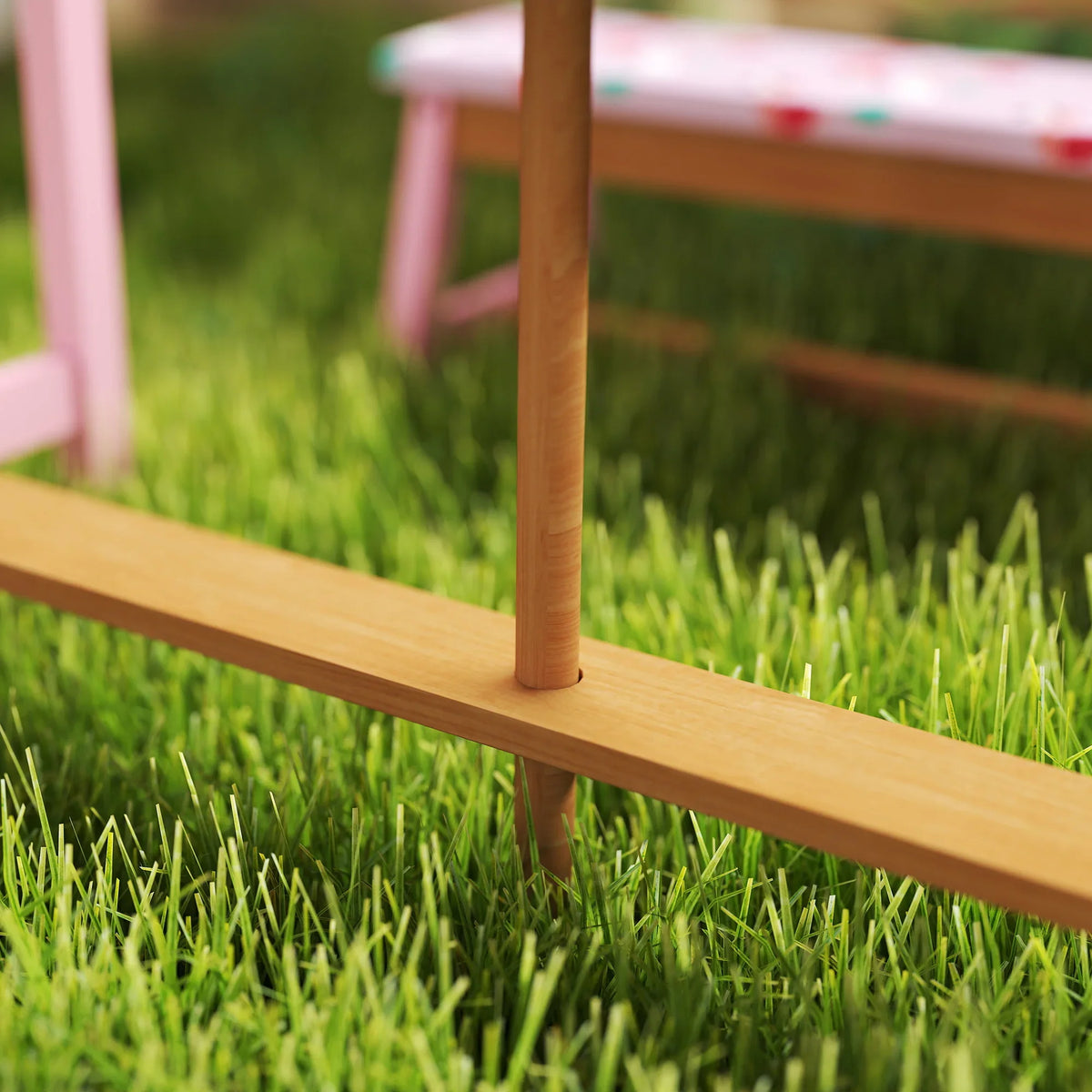 Wooden table leg and tabletop with pink support frame on green grass