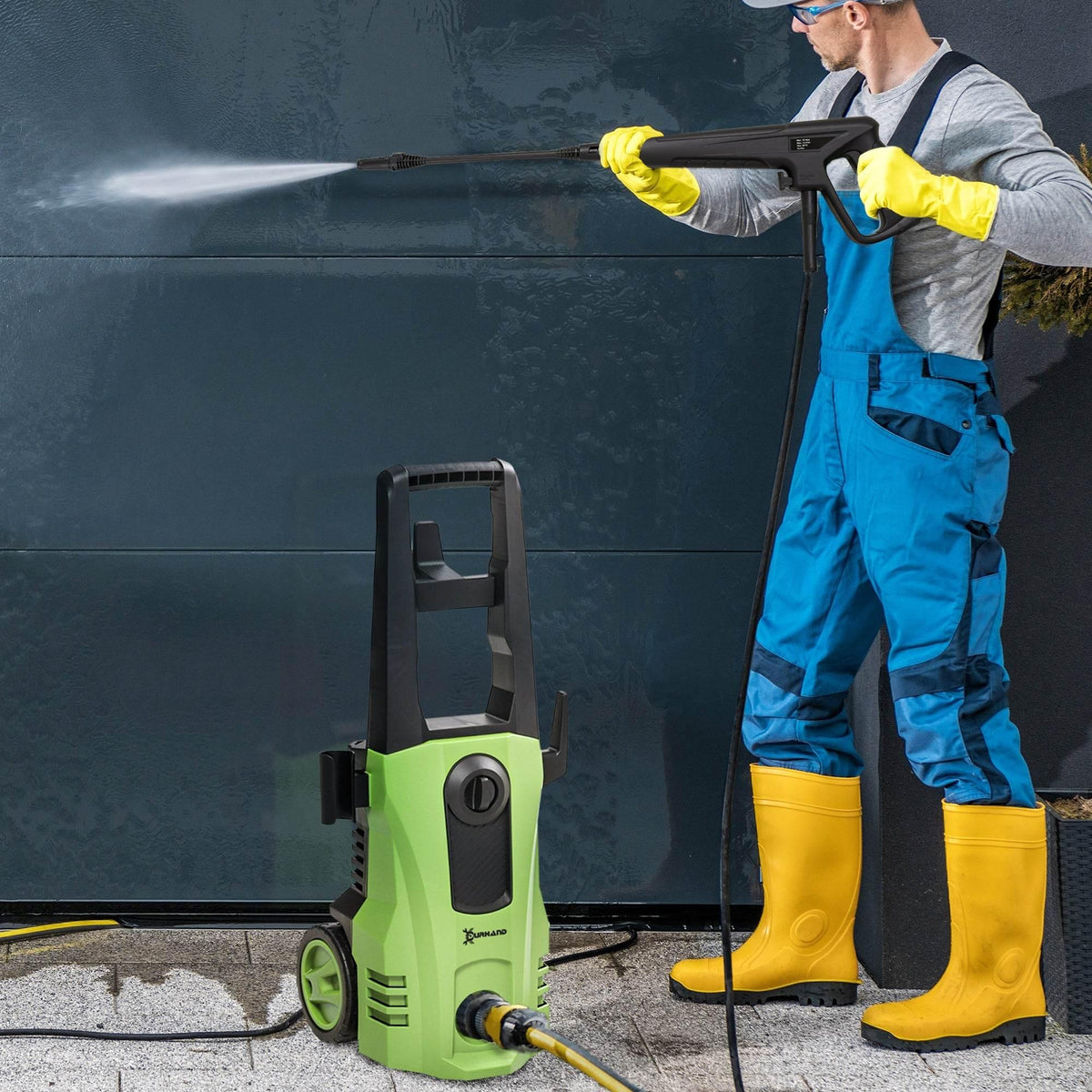 Pressure washer wand spraying water on a wall with yellow gloves