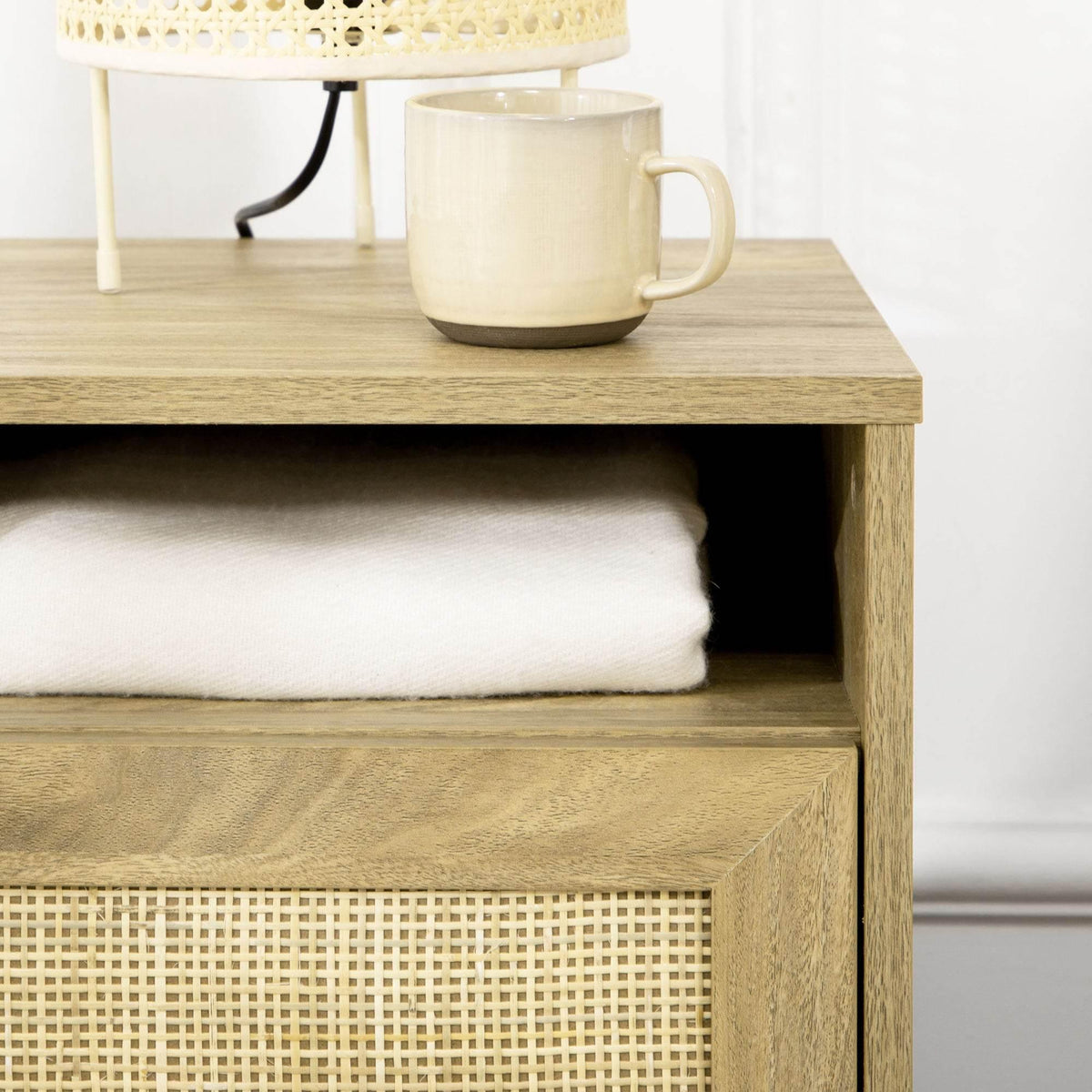 Top open shelf and woven cabinet door front on light wood bedside table
