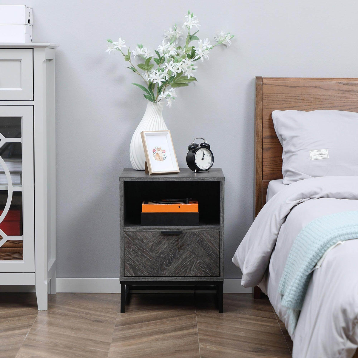Dark gray bedside table with open shelf and drawer in bedroom setting