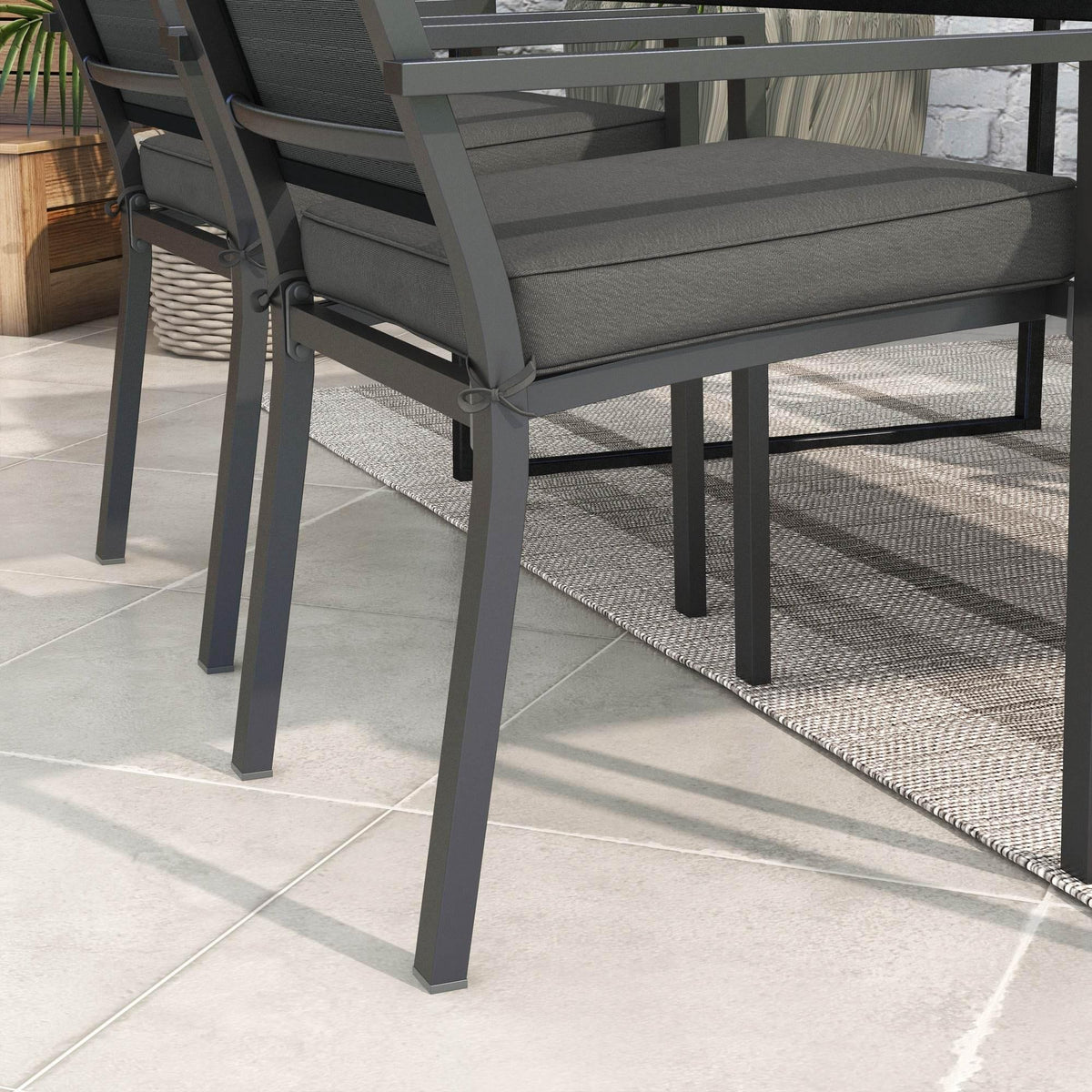 Charcoal grey outdoor chair seat cushion with tied straps on a patio chair