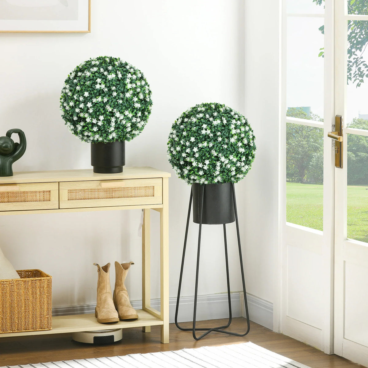 Set of two artificial boxwood topiary balls with white blossoms in black pots and stands