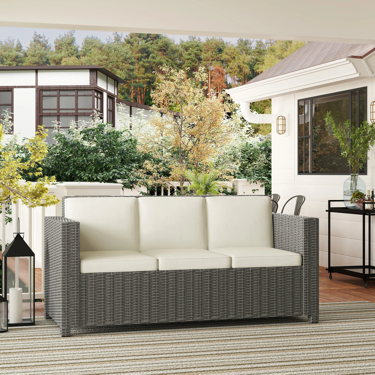 Grey all-weather rattan 3-seater sofa with cream cushions on patio.