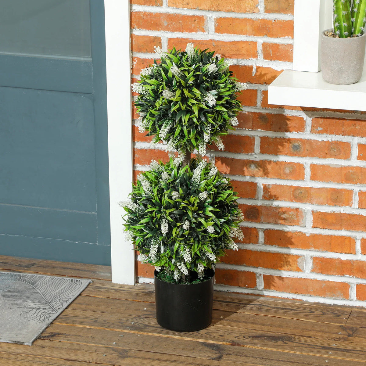 Artificial ball topiary tree with green foliage in black pot on wooden floor