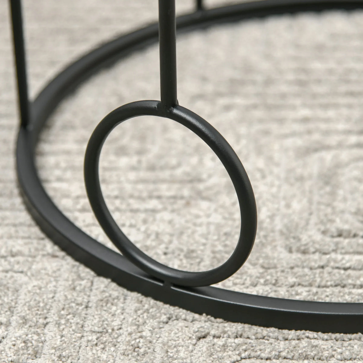 Black metal hoop frame detail on round nesting coffee table base, circular design