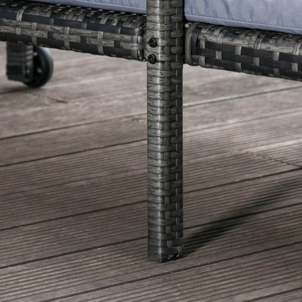 Close-up of dark gray rattan lounge frame corner with casters on wood deck