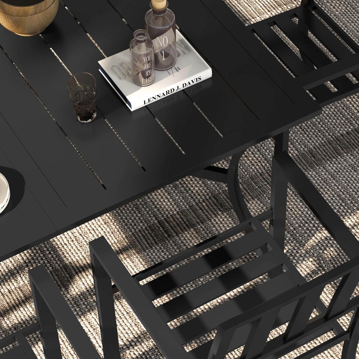 Black outdoor dining table surface with drinks and six slatted chairs, close-up.