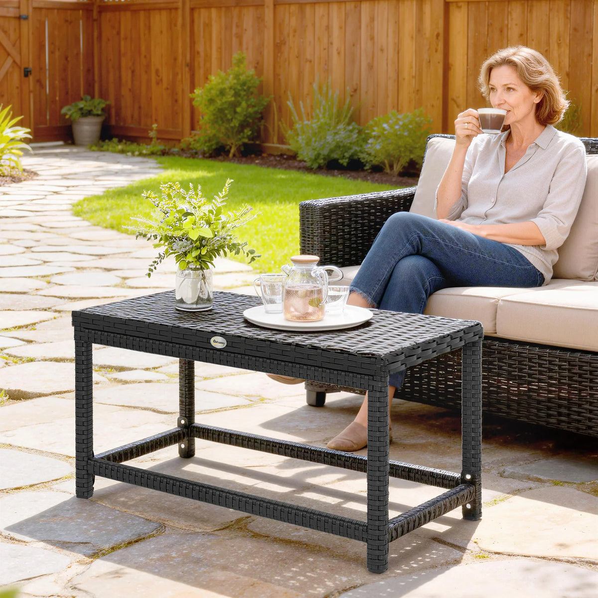 Black outdoor rectangular coffee table with woven top, open lower shelf, and sturdy legs.