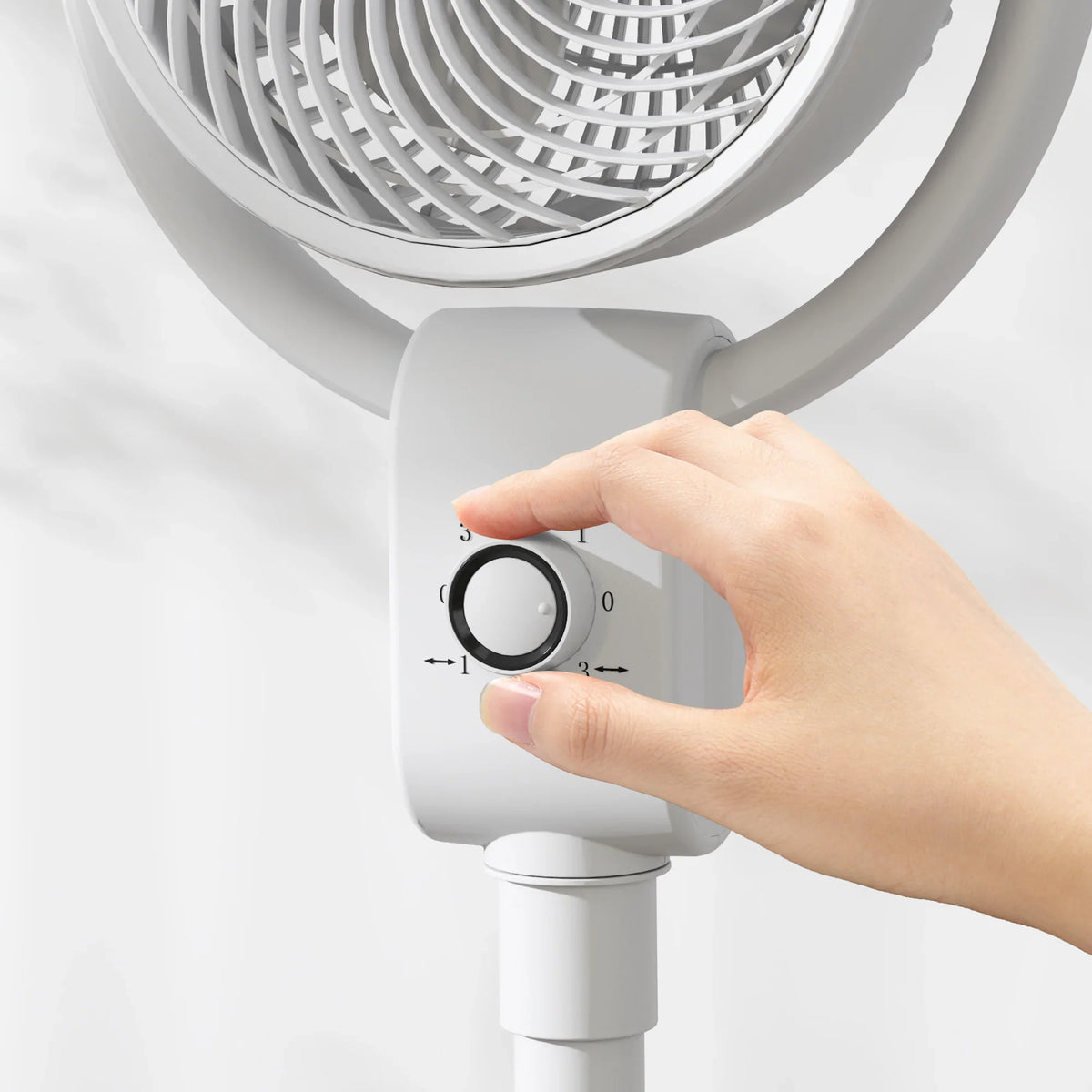 HOMCOM white pedestal fan with hand adjusting the speed control knob