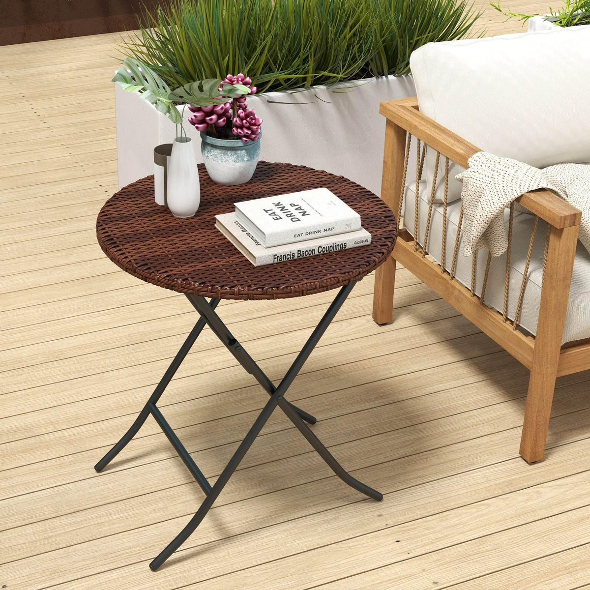 Round brown wicker side table on black X-frame legs, foldable outdoor style