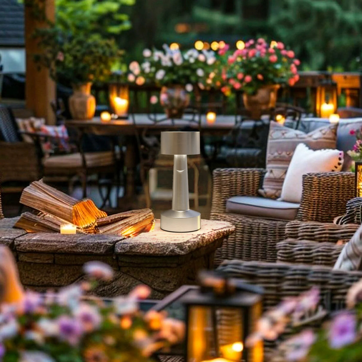 Portable cordless silver table lamp with drum shade glowing on outdoor table