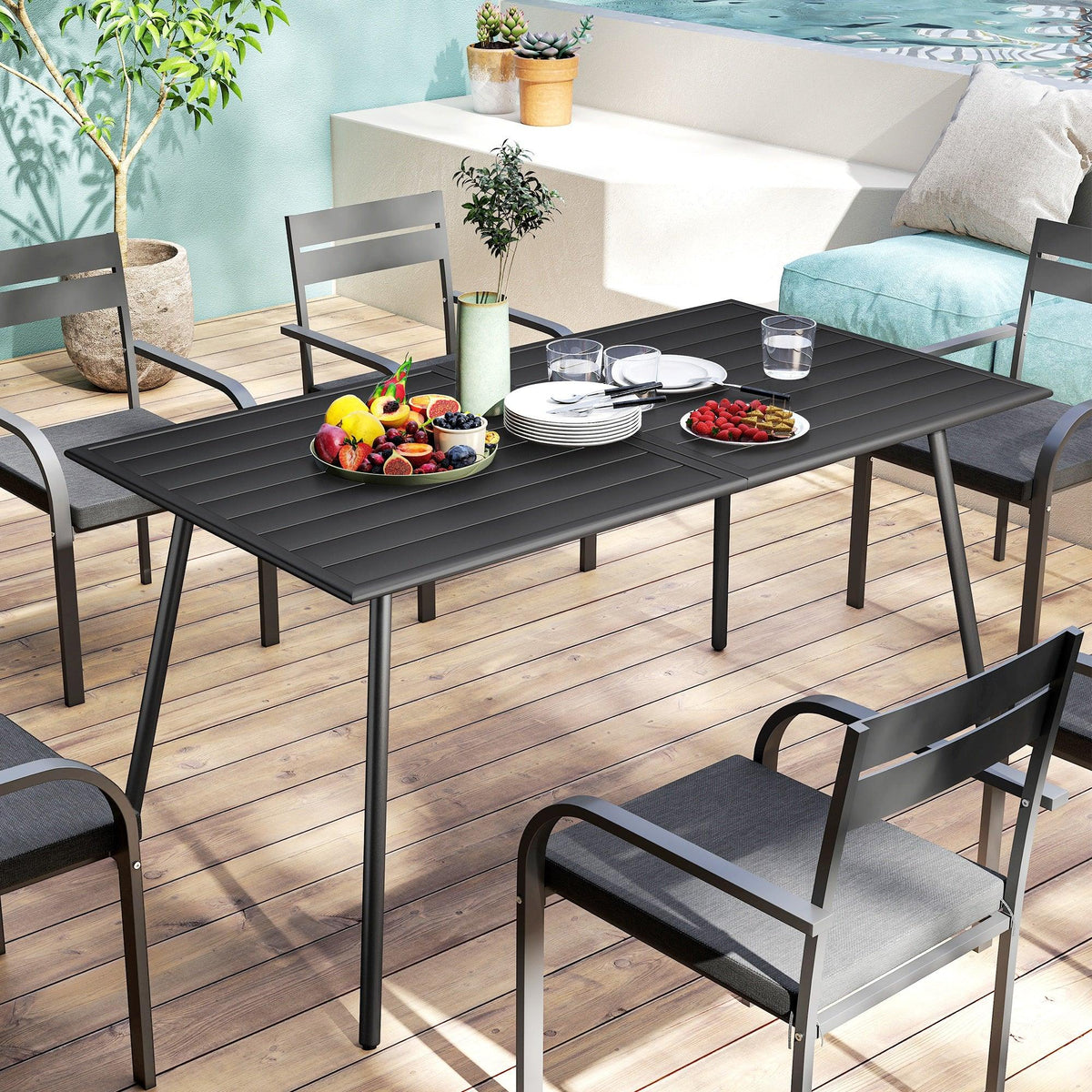 Black outdoor dining table with slat-top and steel frame, set with dishes and fruit