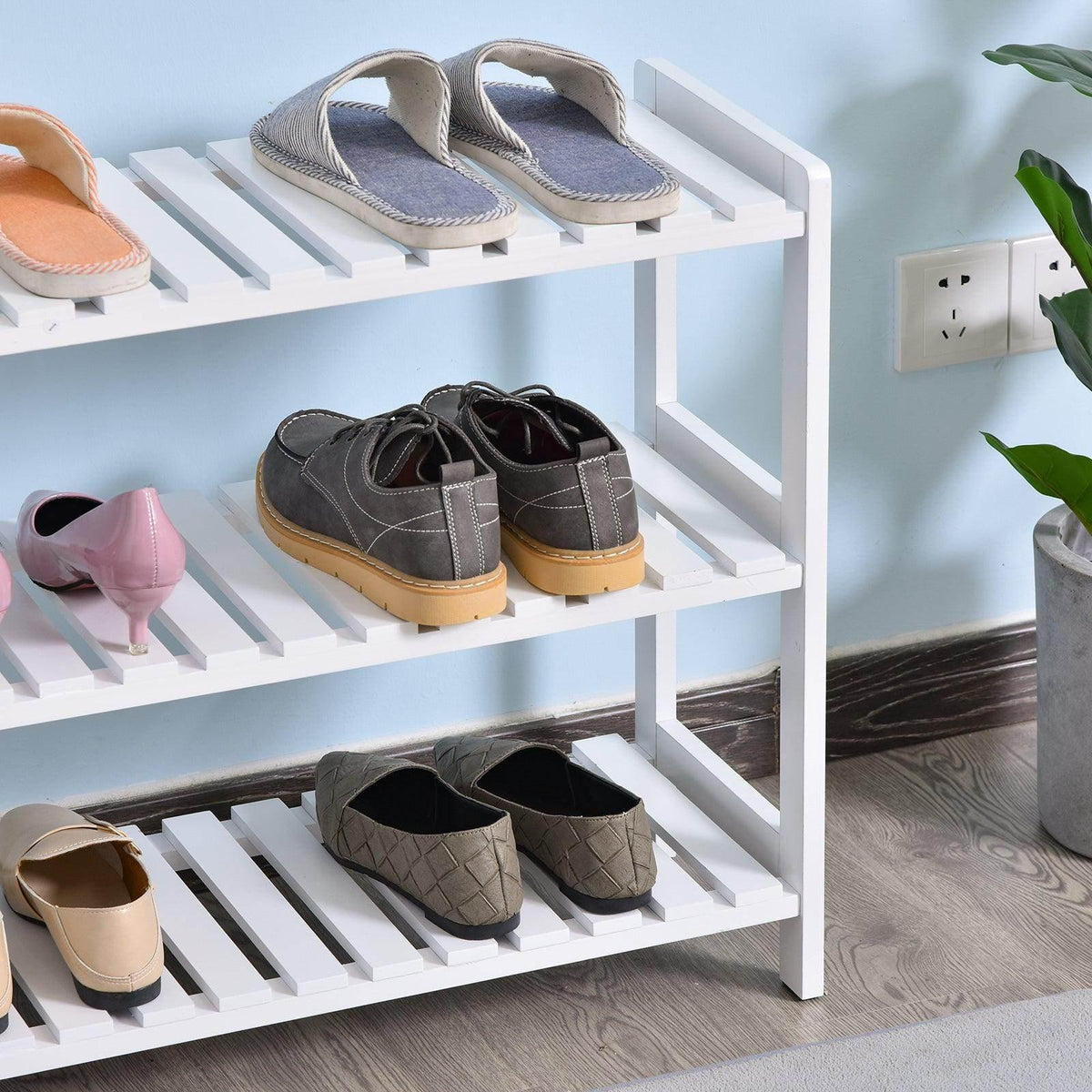 White three-tier shoe rack displaying sandals and dress shoes on slatted shelves.