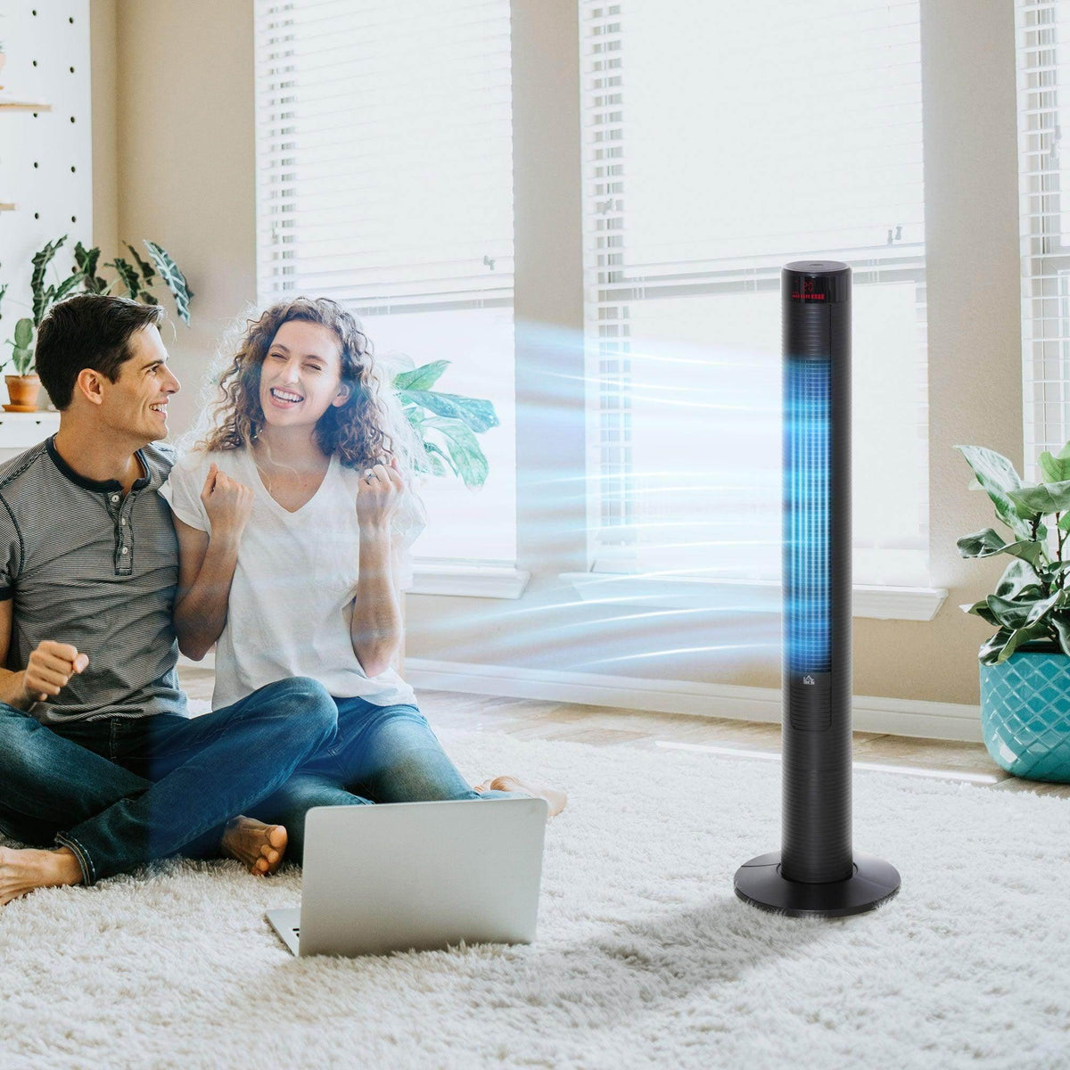 Black tower fan with vertical grille, standing in a living room near a sofa