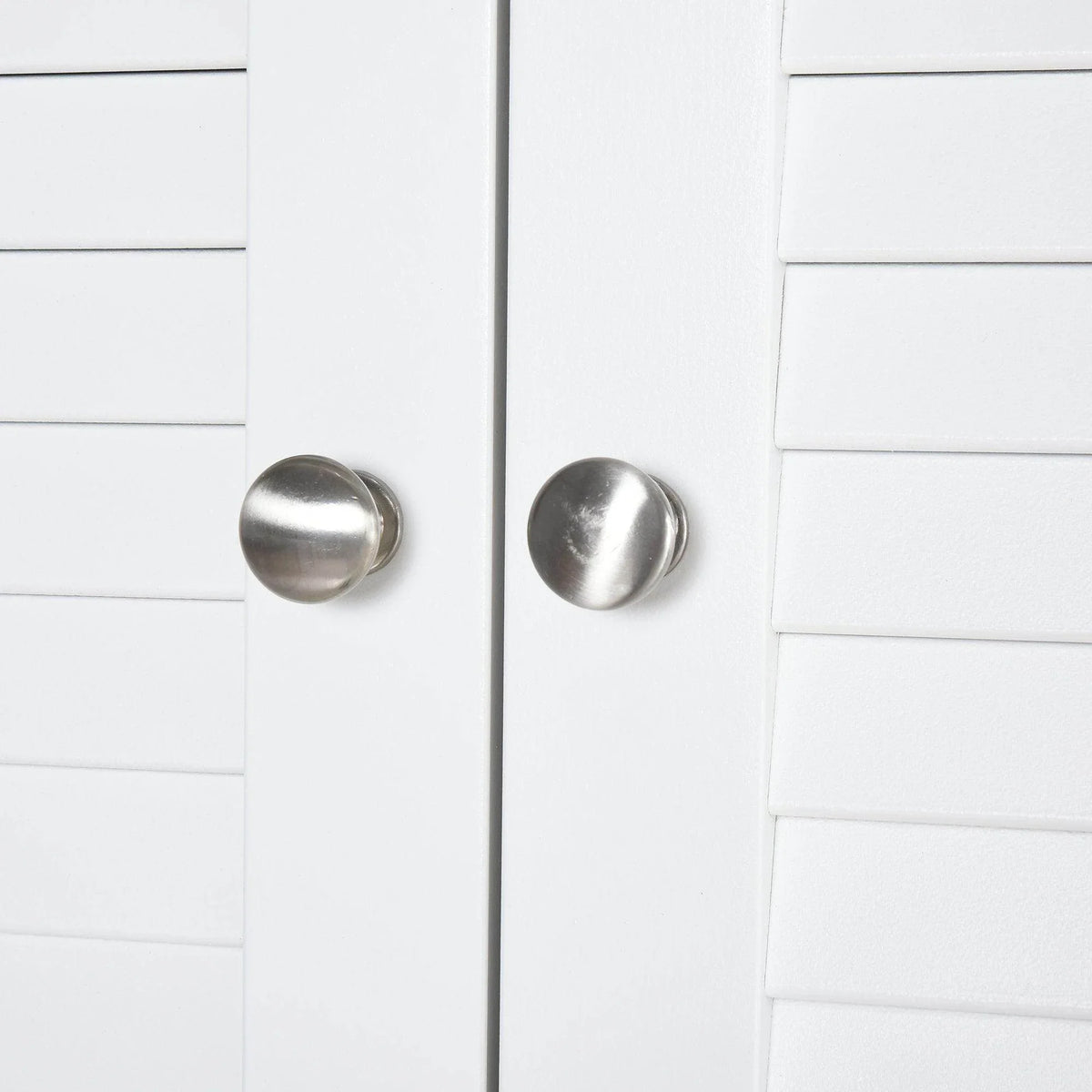 White bathroom storage cabinet with round metal knobs on double louver doors