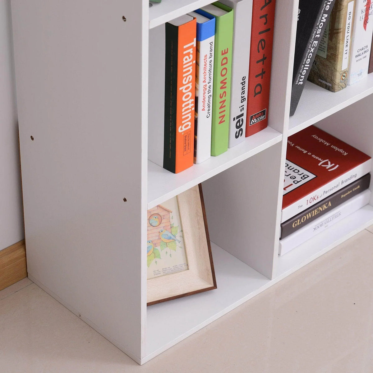 White cube cabinet with side panel and open shelves holding books and framed art