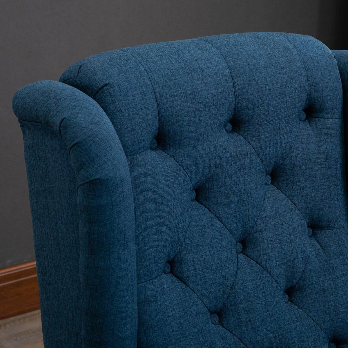 Blue tufted wing-back armchair close-up of button-tufted backrest
