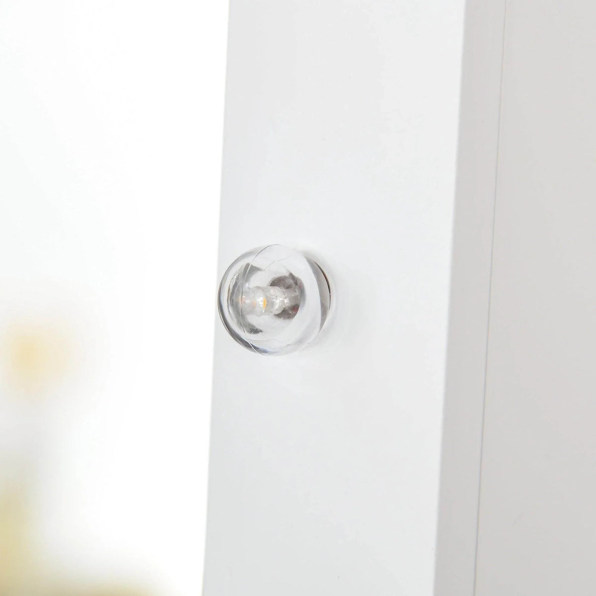 White jewelry cabinet door handle near the mirrored frame