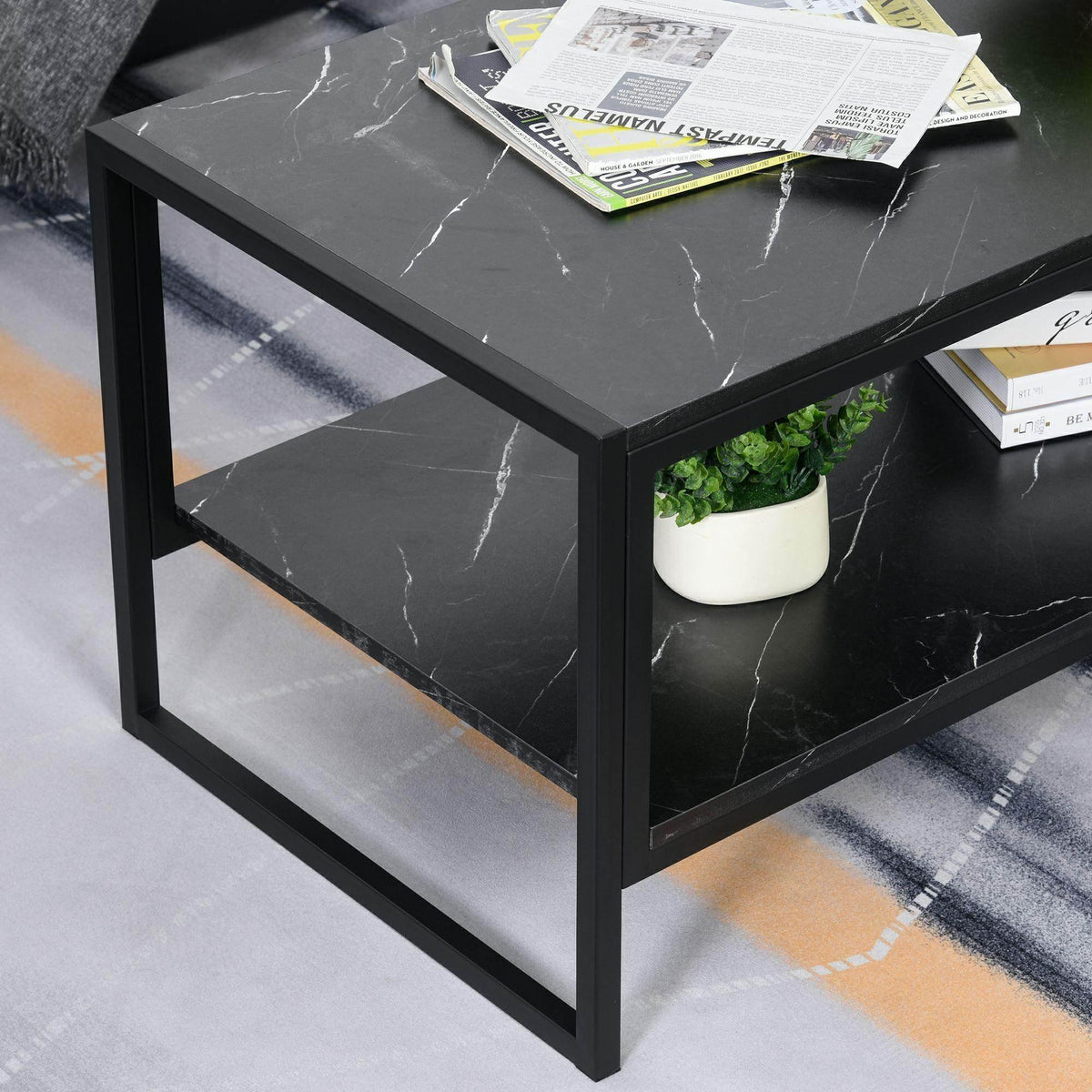 Black marble-print coffee table with lower shelf and steel sides, tabletop with magazines