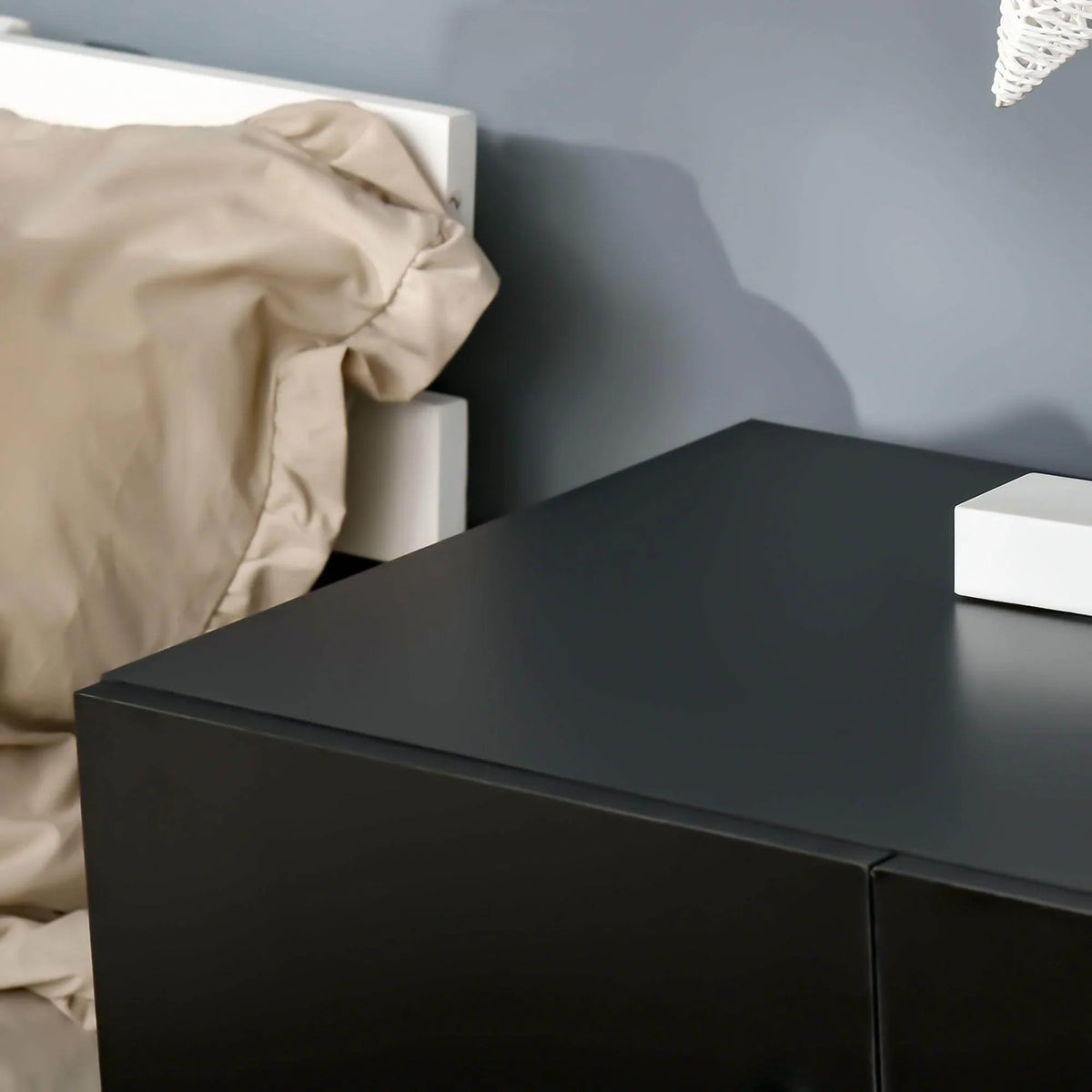 Black storage cabinet top edge with smooth doors and round chrome knobs, close-up