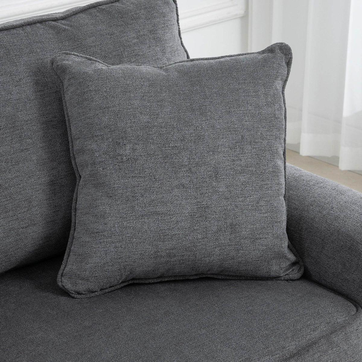 Gray square throw pillow on a gray loveseat seat