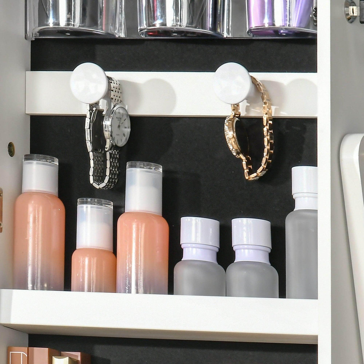Jewelry cabinet shelf with beauty bottles and small hoop earrings on black backing
