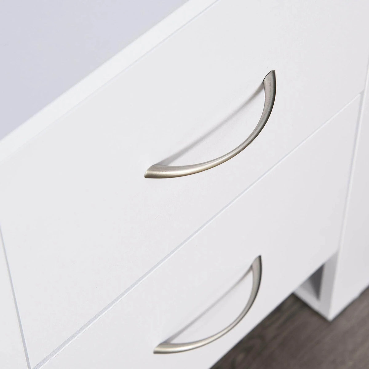 Close-up of white drawer fronts with curved metal pull handles