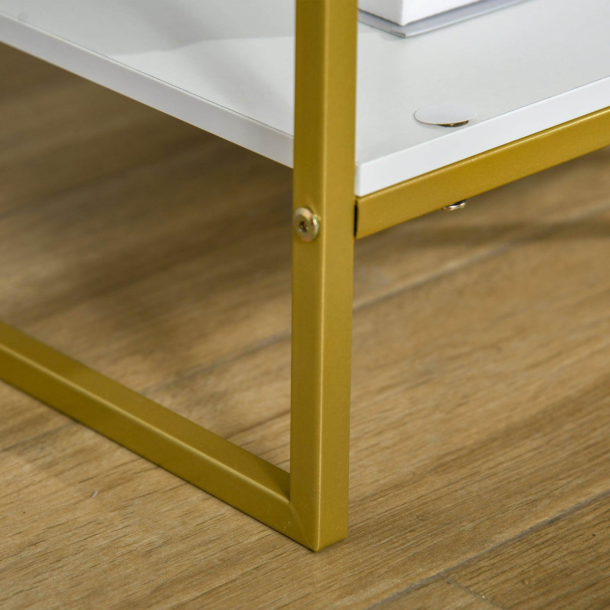 Gold metal corner leg and base frame of a white nightstand, with floor contact pads