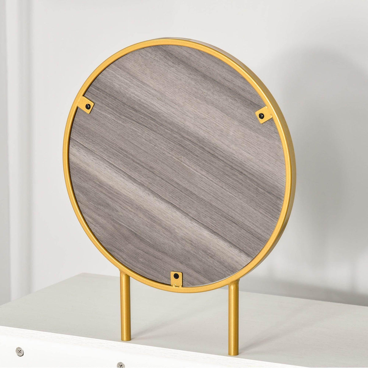 Round vanity mirror with gold frame and gray backing, standing on two legs