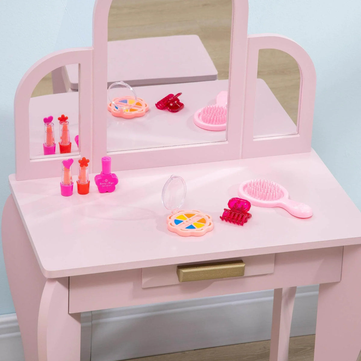 Pink kids vanity table with two shelves and assorted accessories on tabletop