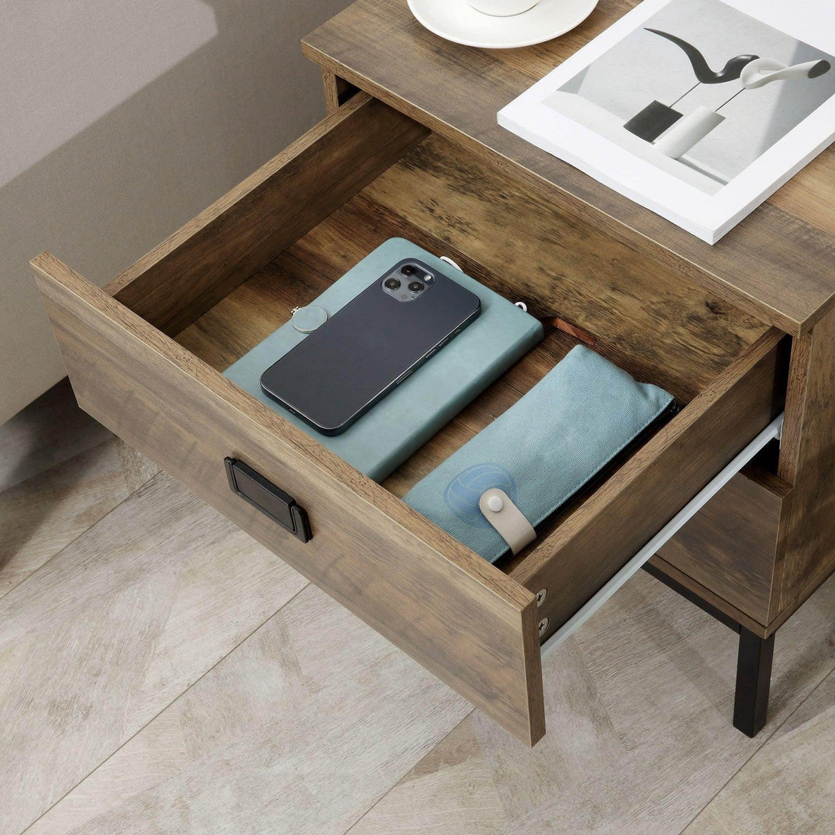 Retro bedside table with open drawer holding a phone and fabric items, black pull