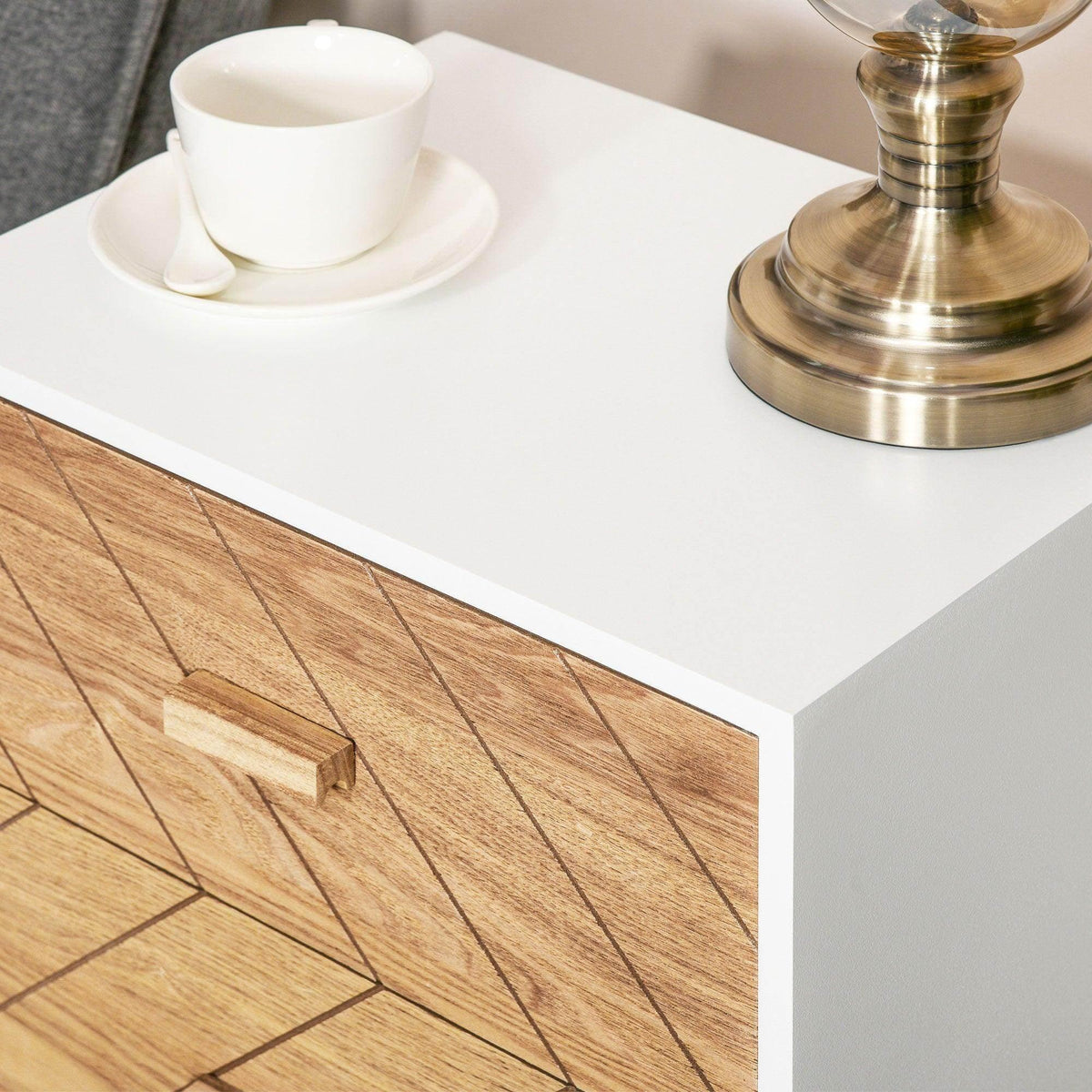 Bedside table drawer front with light wood geometric pattern and metal pull, white top.