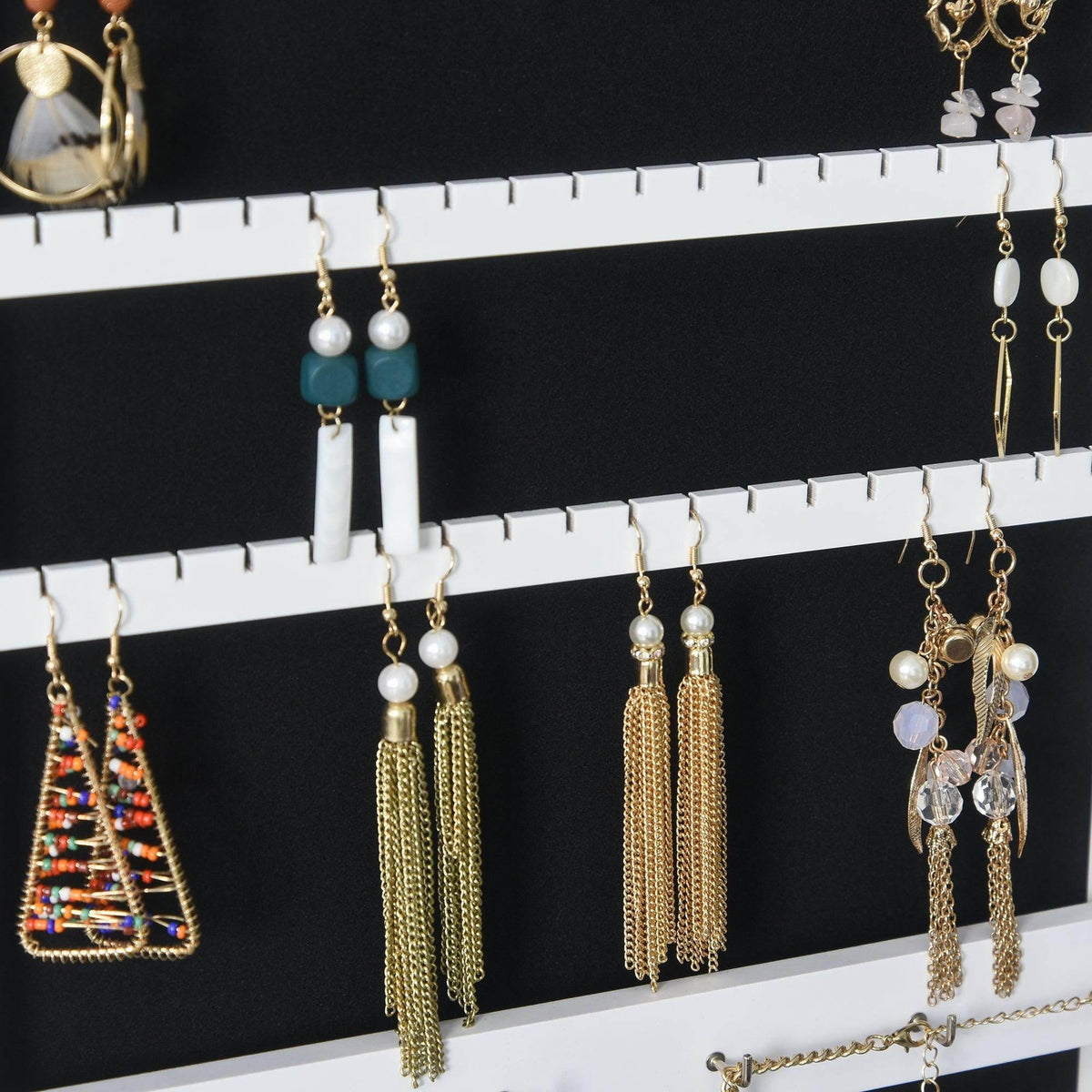 White jewelry cabinet interior with hanging earring hooks and multiple earrings