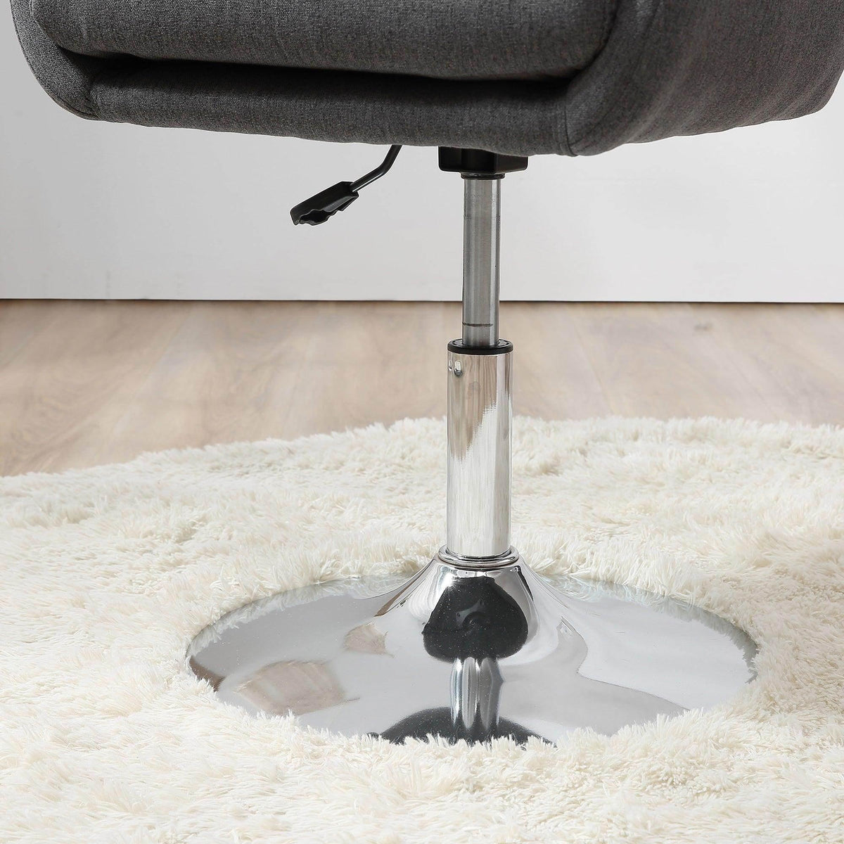 Chrome pedestal base with round footplate under dark grey swivel tub chair