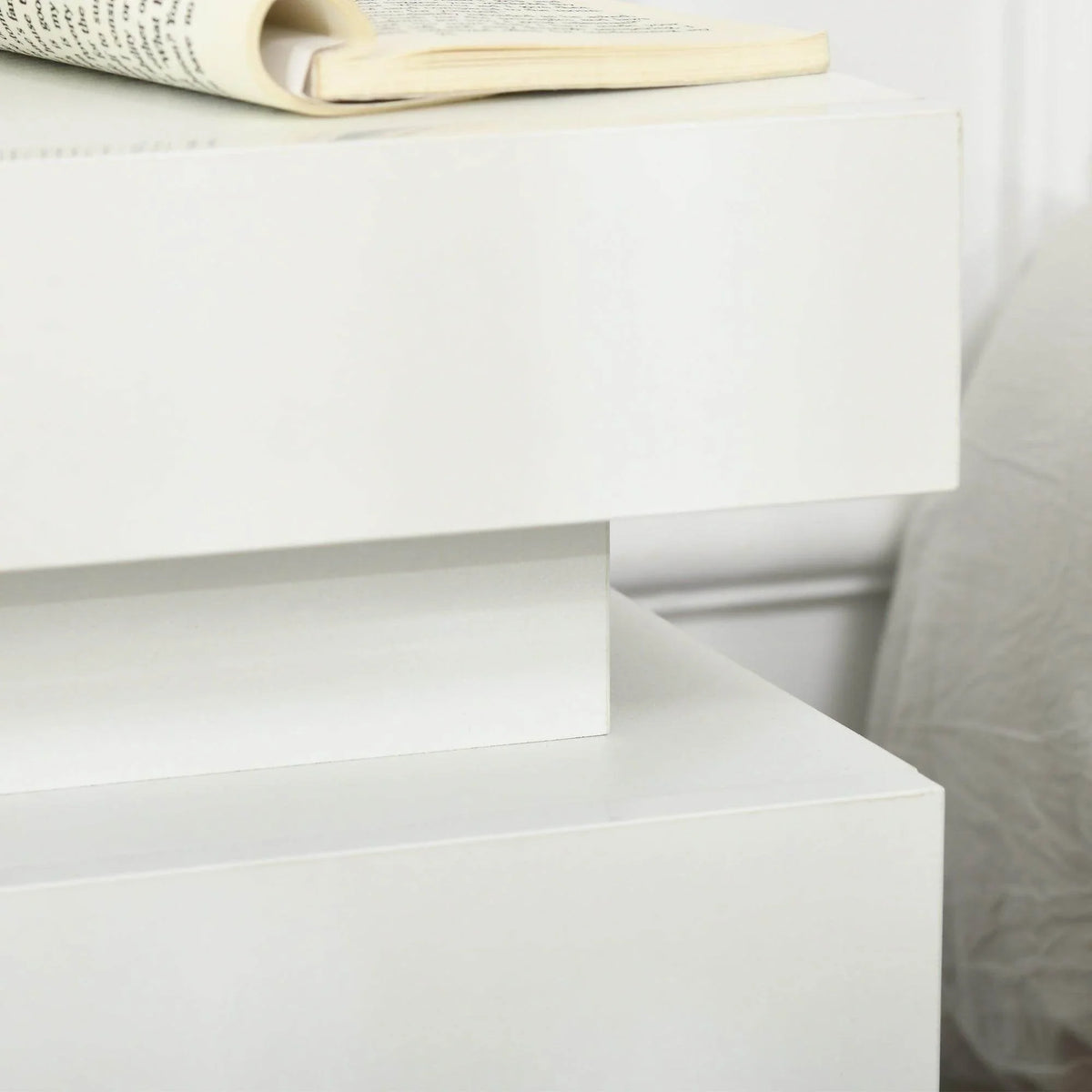 White bedside table drawer front and top panel detail, smooth glossy surface