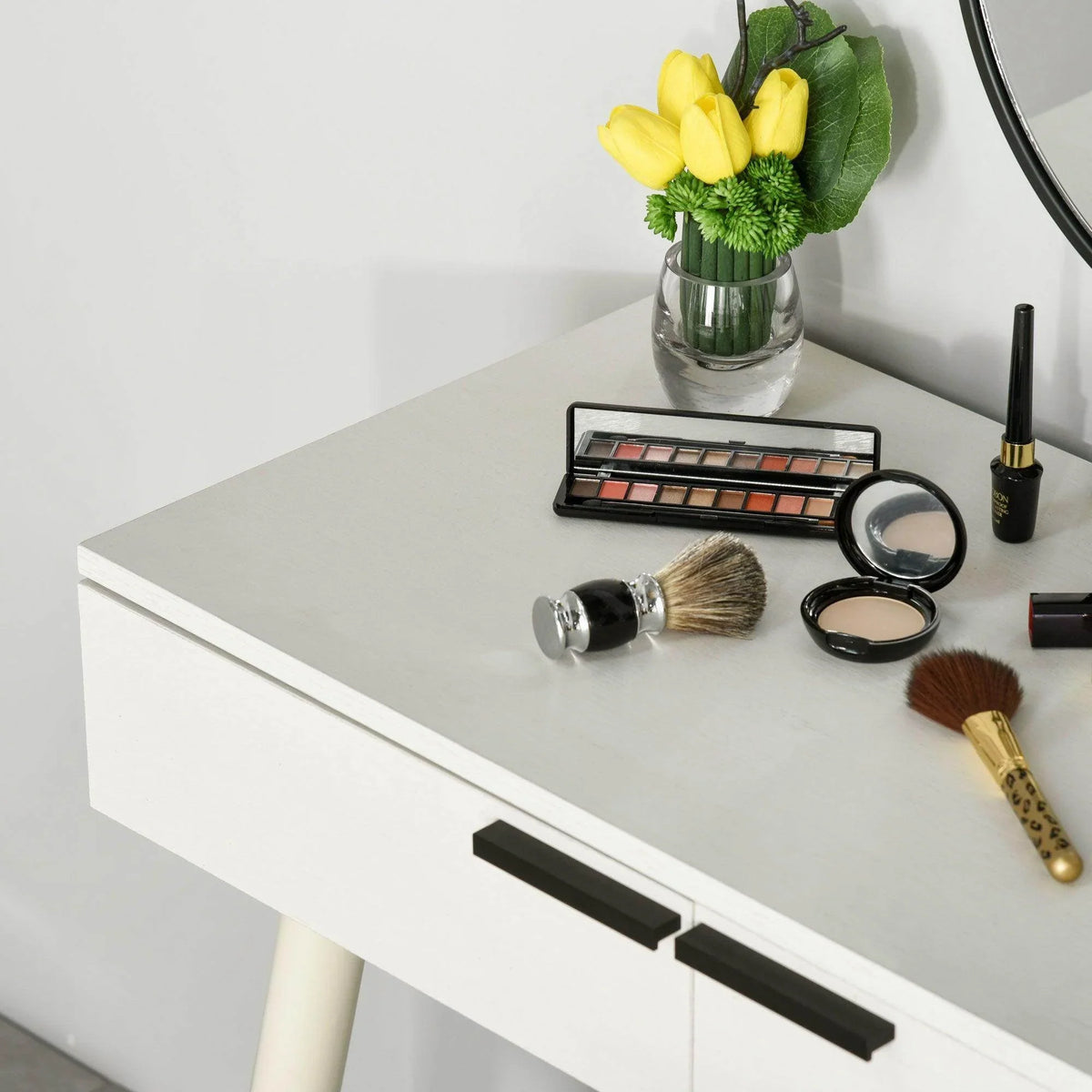 White vanity table with long black drawer handles, mirror, and gray cushioned stool