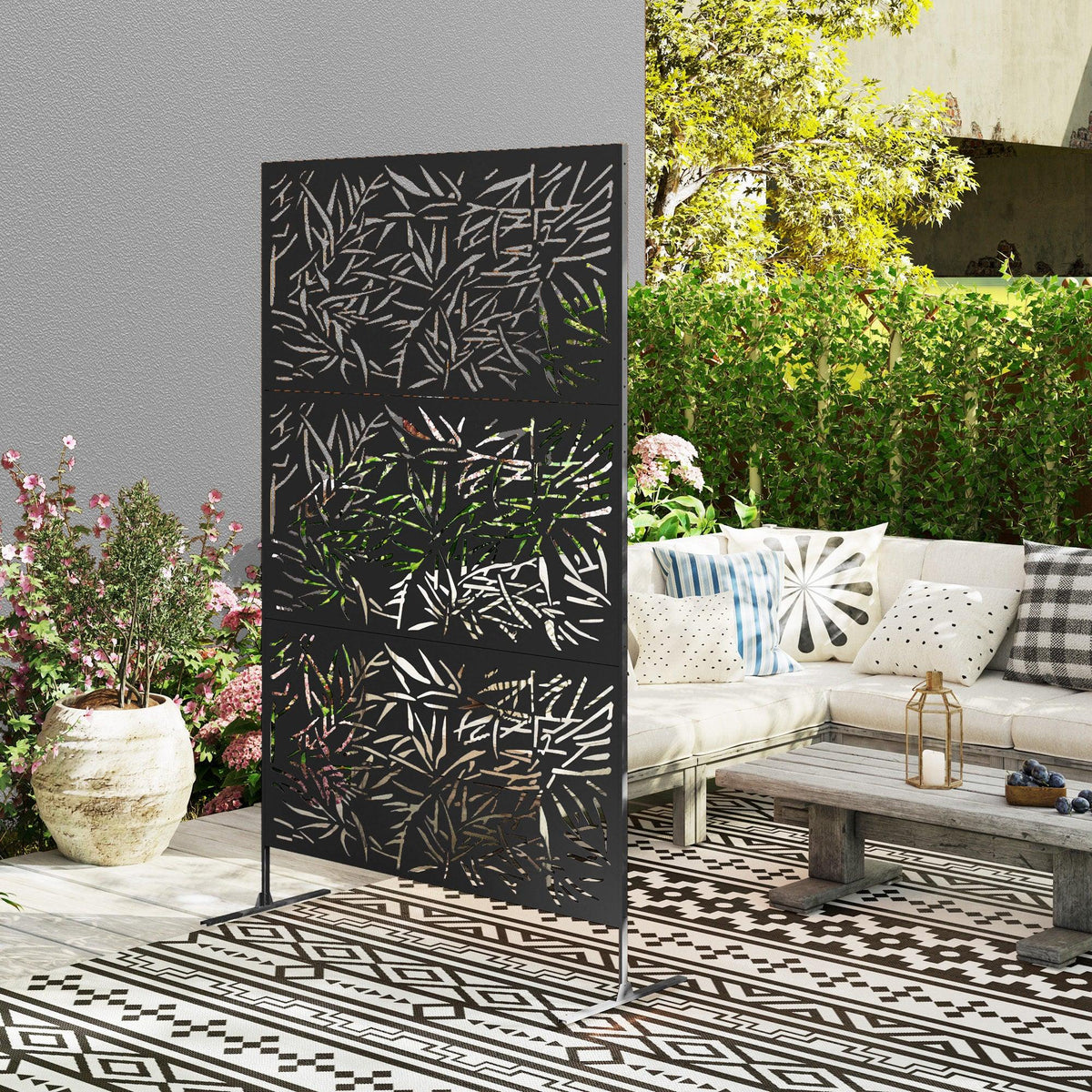 Black bamboo-style privacy screen with leaf cutout panel standing in outdoor patio area