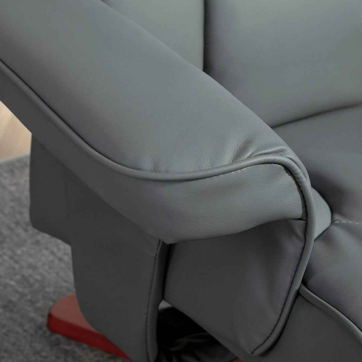 Gray faux leather reclining chair armrest and side panel with stitched seams, close-up