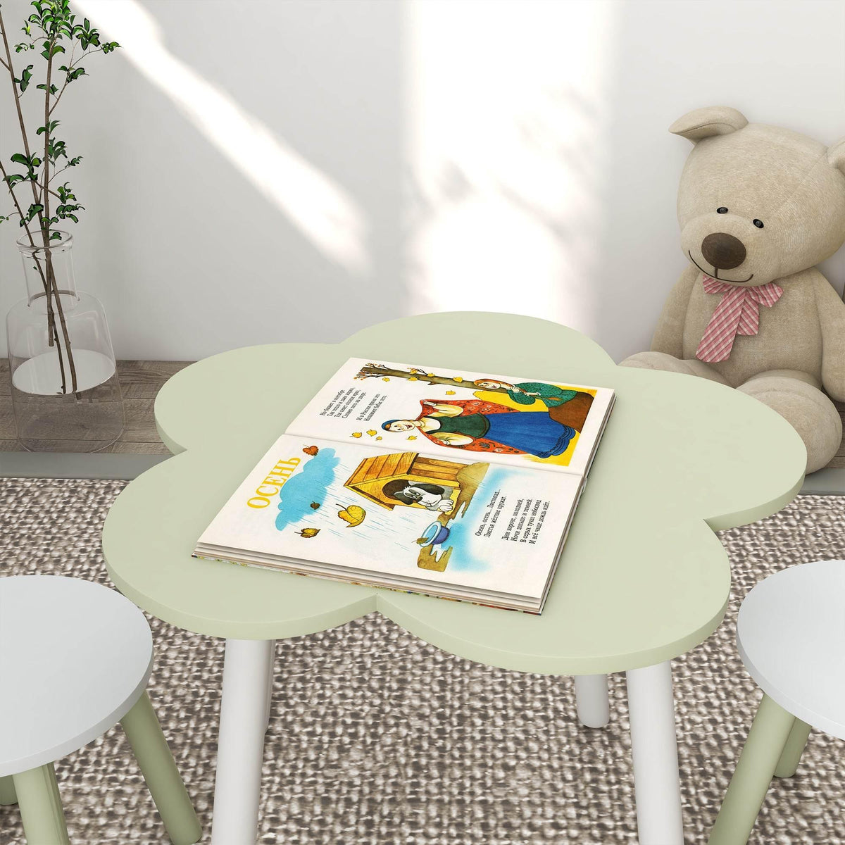 Round light green kids table with white legs and a book on top