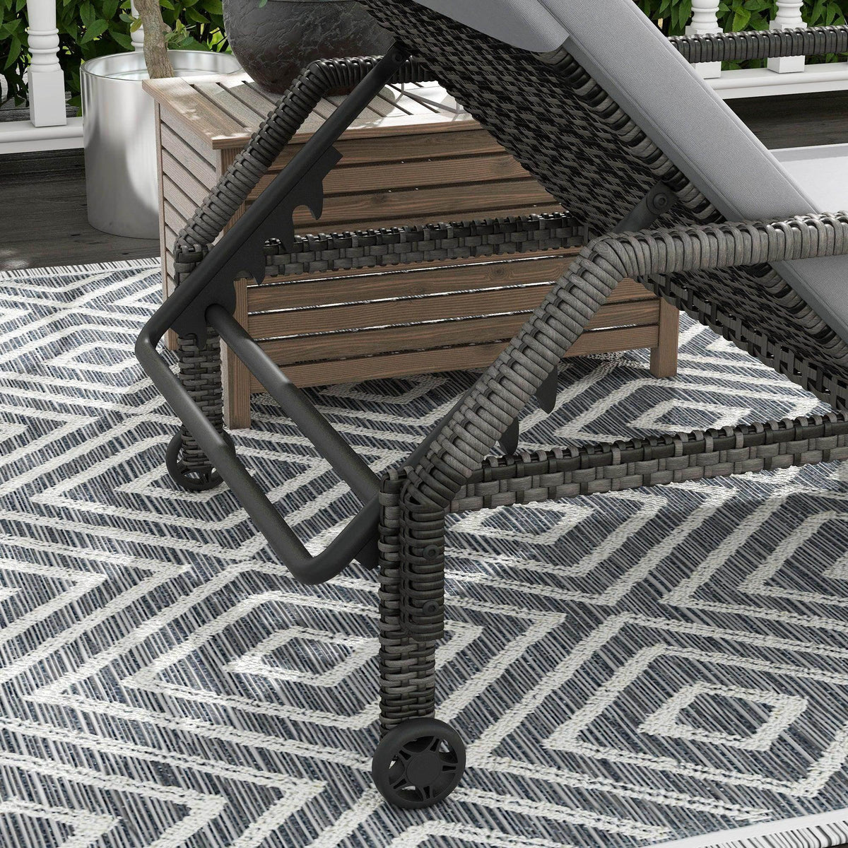 Outdoor rattan chaise lounger with dark wicker base, gray cushion, and rolling caster wheel