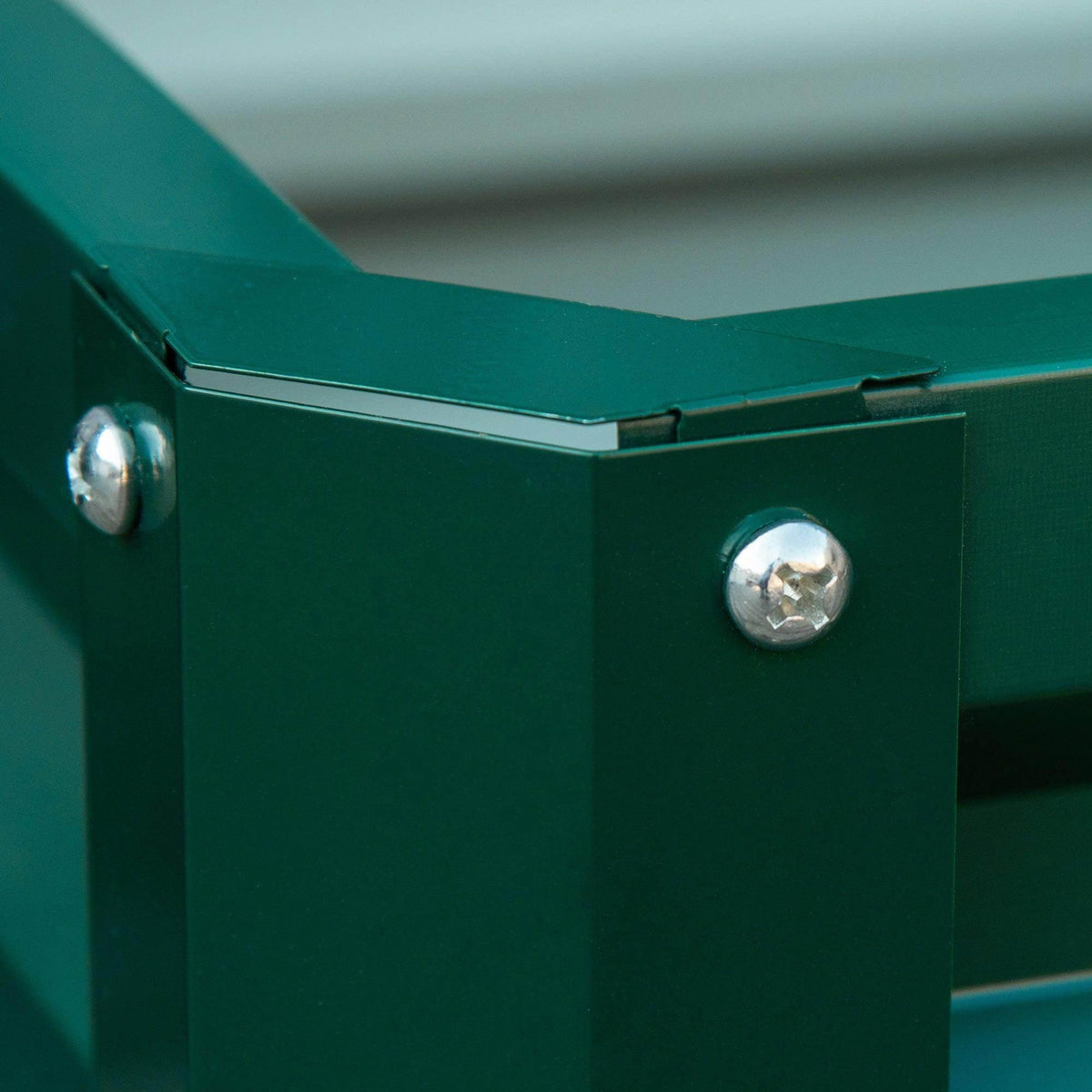 Green raised garden bed corner with metal support and shiny bolts, slatted side