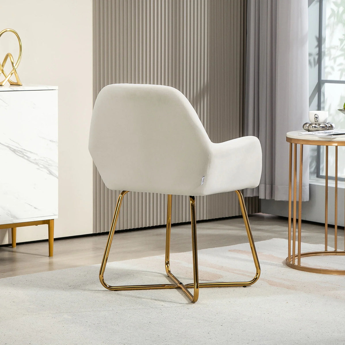 Cream accent arm chair with rounded back, curved arms, and gold metal sled base