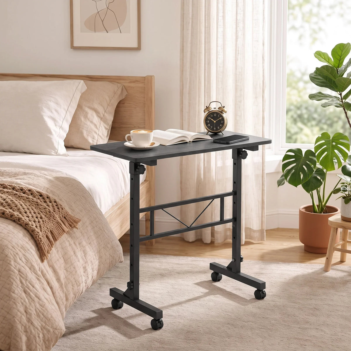Adjustable overbed table beside bed with black top, metal frame, and rolling casters