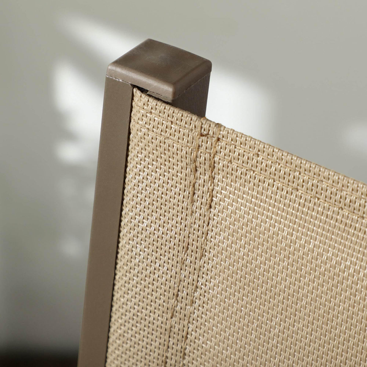 Close-up of beige woven mesh seat edge with dark brown metal frame