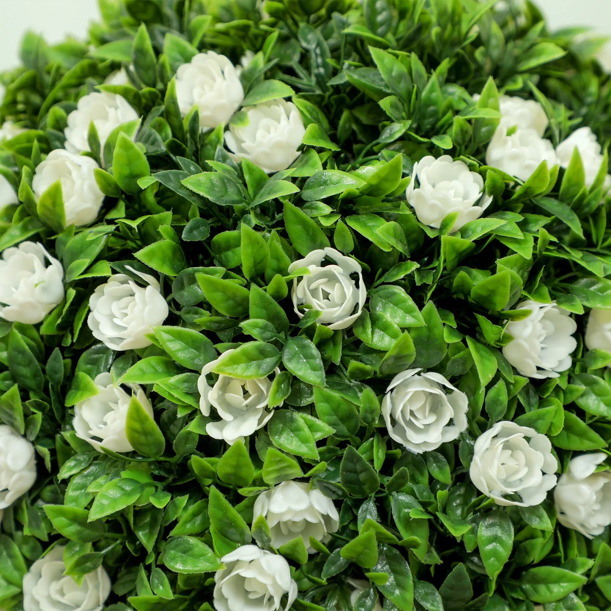 Close-up of artificial rose topiary ball with white rose blooms and green leaves